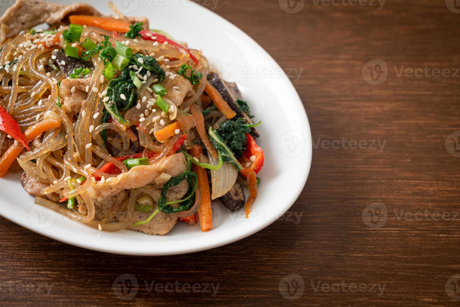 japchae o vermicelli coreani saltati in padella con verdure e maiale conditi con sesamo bianco foto