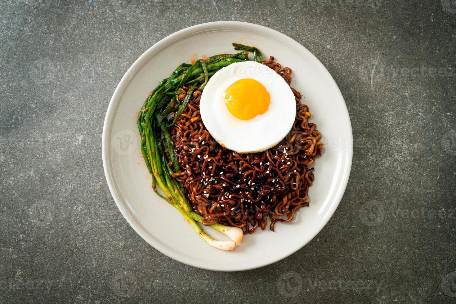 noodles istantanei con salsa nera piccante coreana essiccata con uovo fritto e kimchi foto