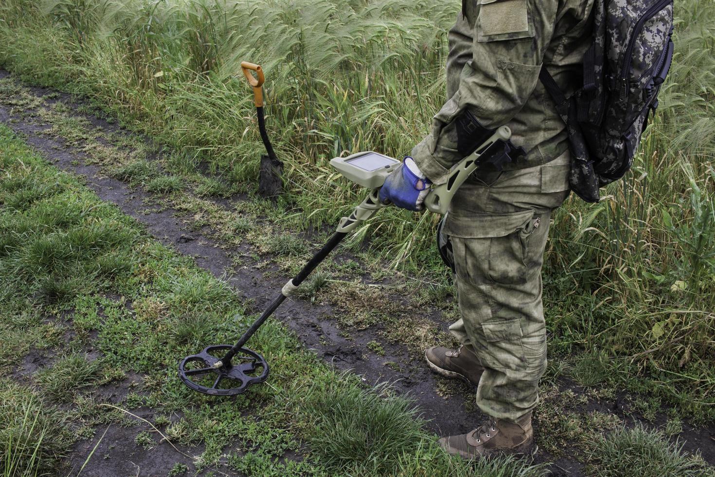 soldato che usa un metal detector nei campi foto