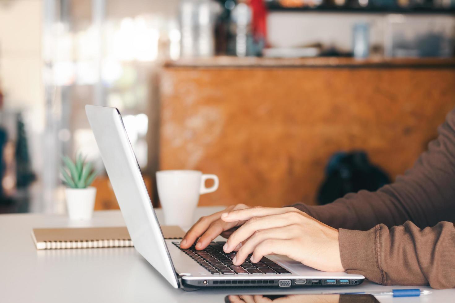 l'uomo d'affari che prende appunti riassume la riunione online con il laptop, lavora da solo, seduto alla tua scrivania. lavorare da casa, mani ravvicinate. foto