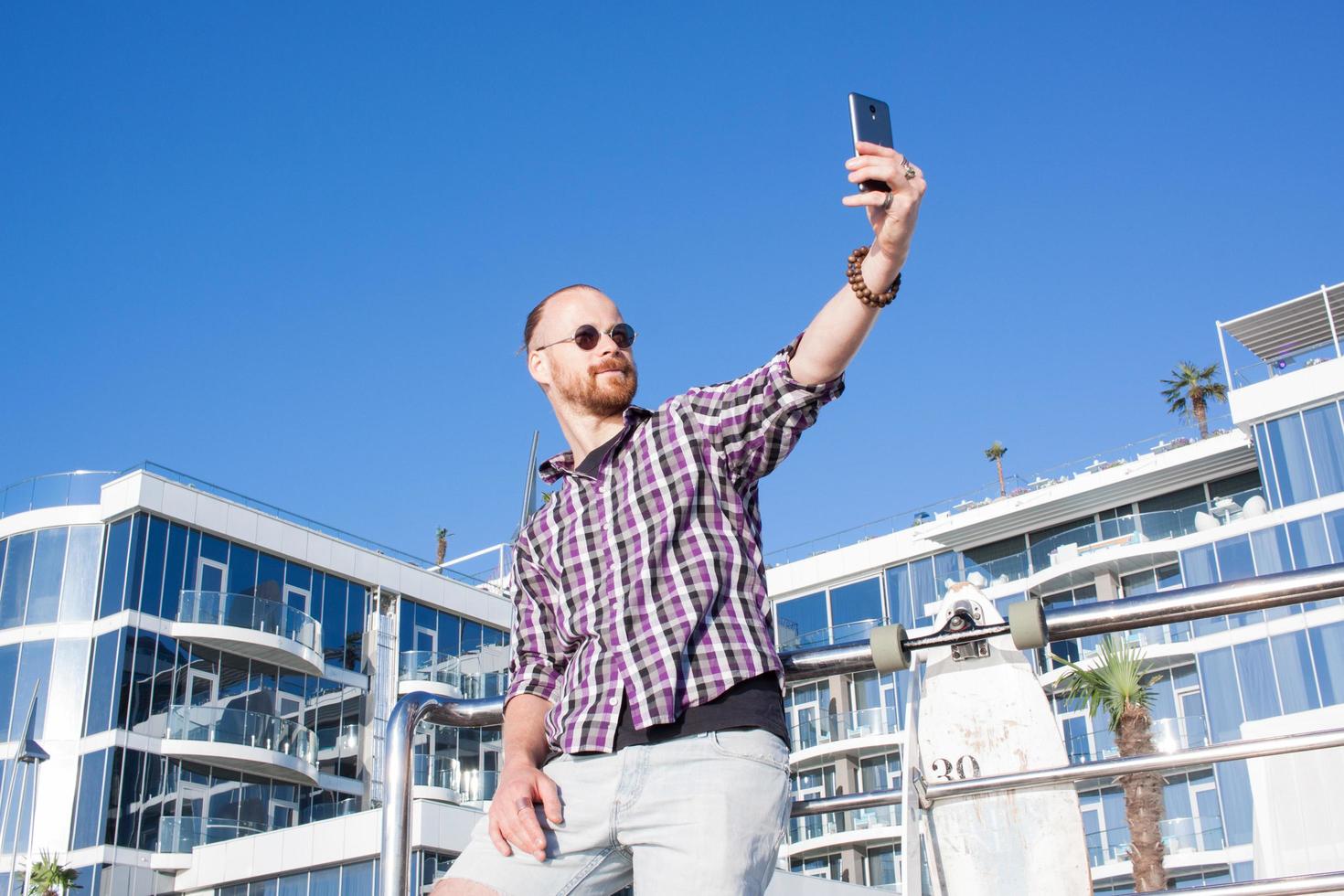 il giovane uomo barbuto fa selfie sul telefono foto