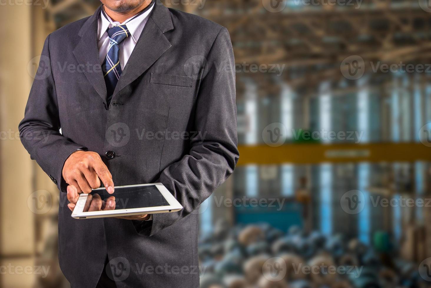 l'uomo d'affari è in possesso di tablet con sfondo di fabbrica gru a ponte della fabbrica di bobine d'acciaio foto