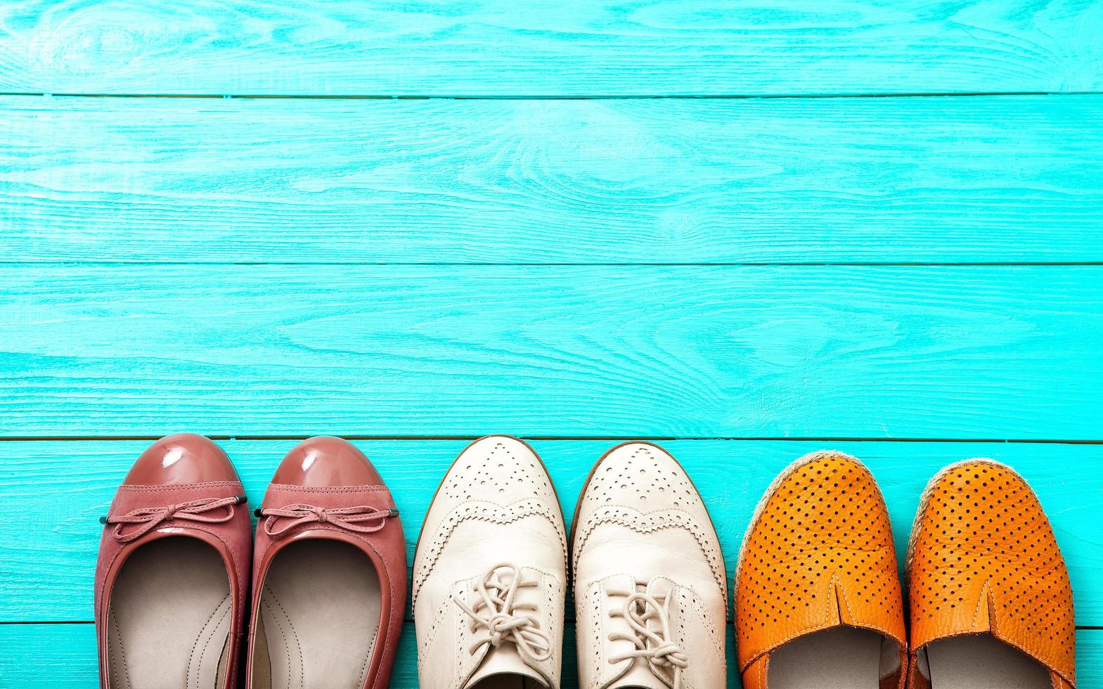 diverse paia di scarpe femminili su pavimento in legno blu, vista dall'alto e spazio per la copia foto