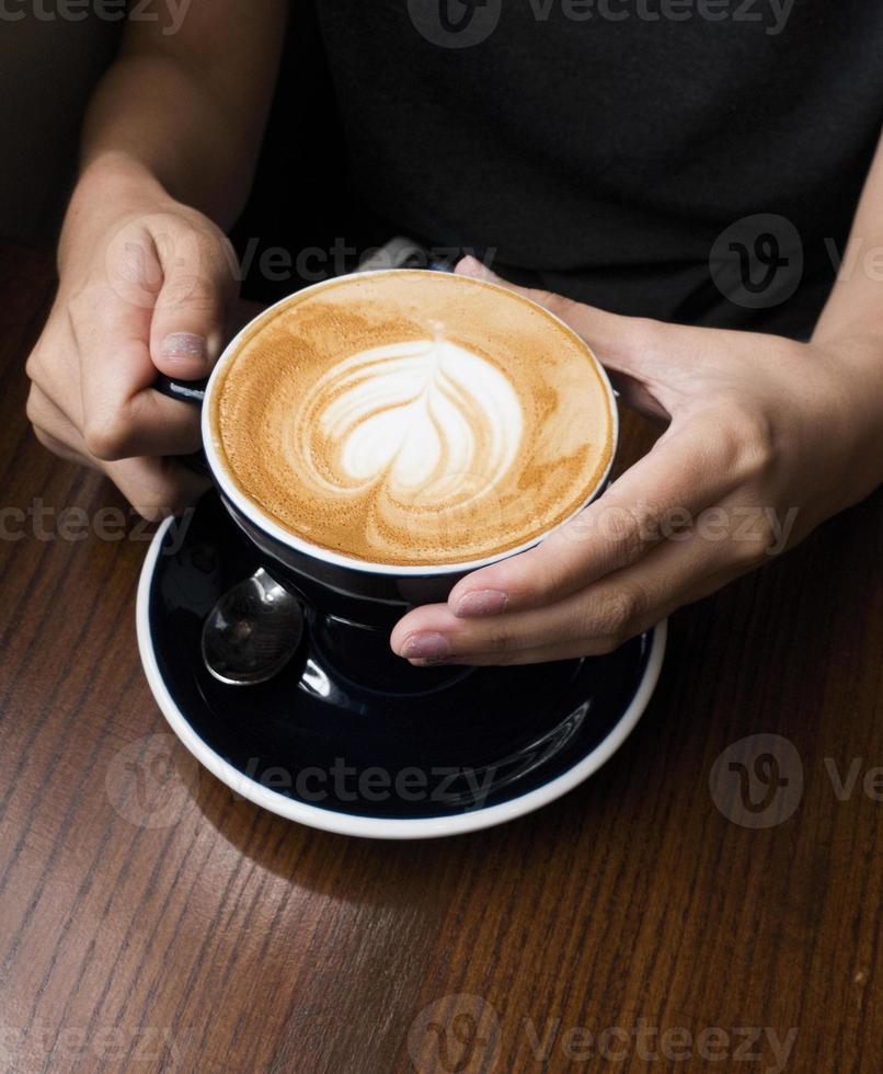 caffè latte in mano. sfondo scuro foto
