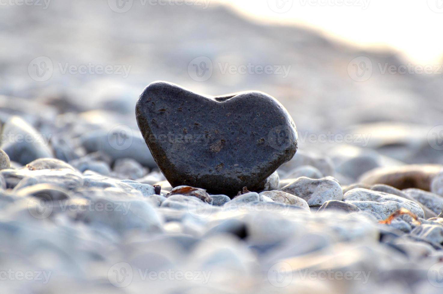 pietra a forma di cuore sullo sfondo della spiaggia. giornata di sole estivo. concetto di amore, matrimonio e San Valentino. trovare pietre belle e interessanti. vacanza al mare foto
