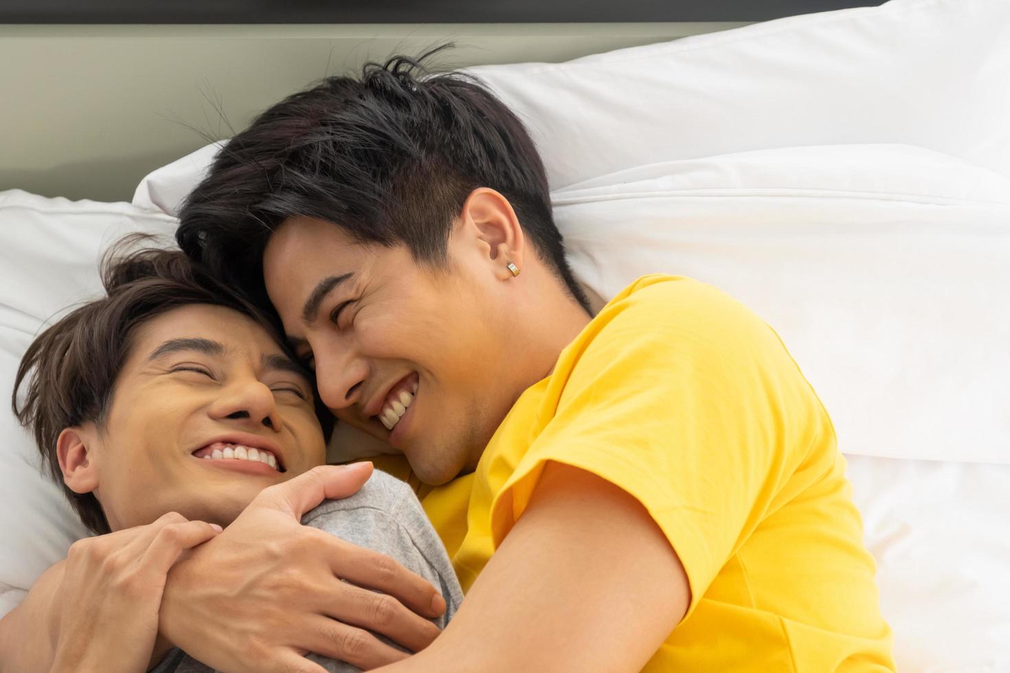 coppia omosessuale gay asiatica si abbraccia e si abbraccia sul letto. uguaglianza di genere e giusto concetto, momento giocoso e romantico. foto