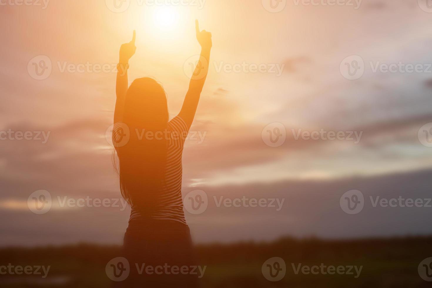 silhouette di donna che prega su sfondo bellissimo cielo foto