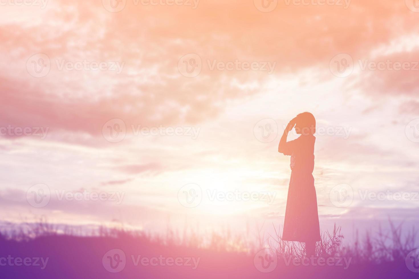 silhouette di donna che prega su sfondo bellissimo cielo foto