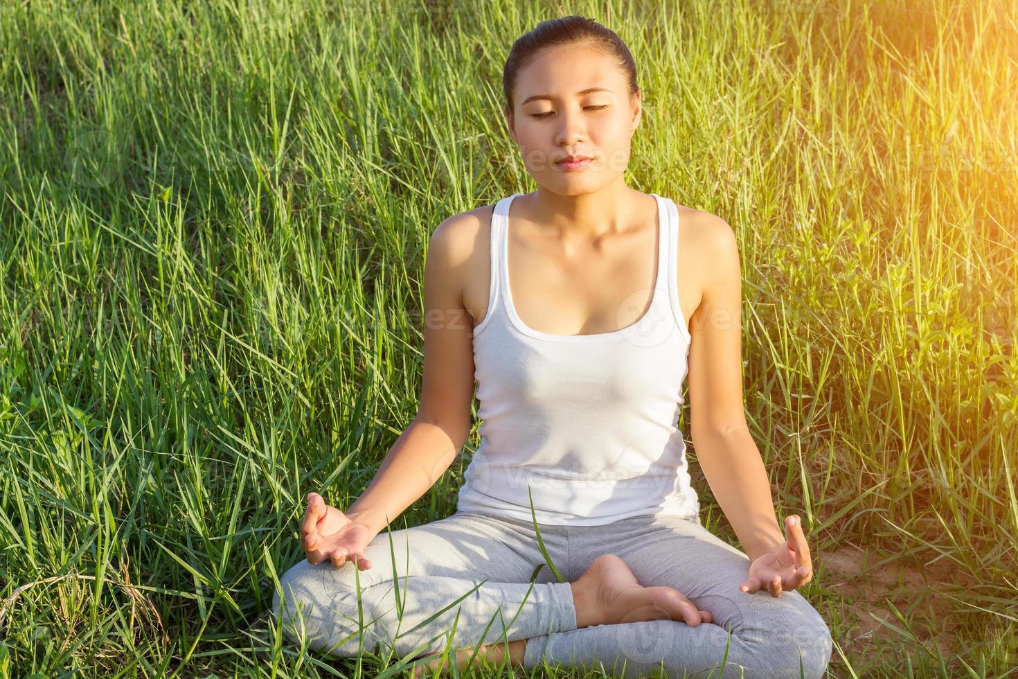 yoga in città bella giovane donna in forma che indossa abbigliamento sportivo meditando, respirando, seduta con le gambe incrociate in posizione di mezzo loto per strada il giorno d'estate, ardha padmasana, copia spazio foto