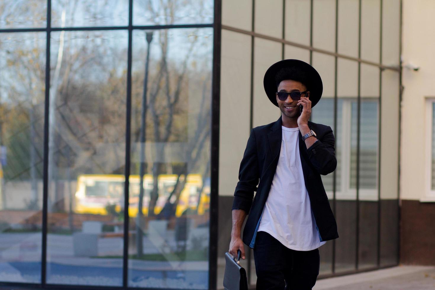giovane maschio felice in abito nero e cappello nero, concetto di uomo d'affari moderno foto