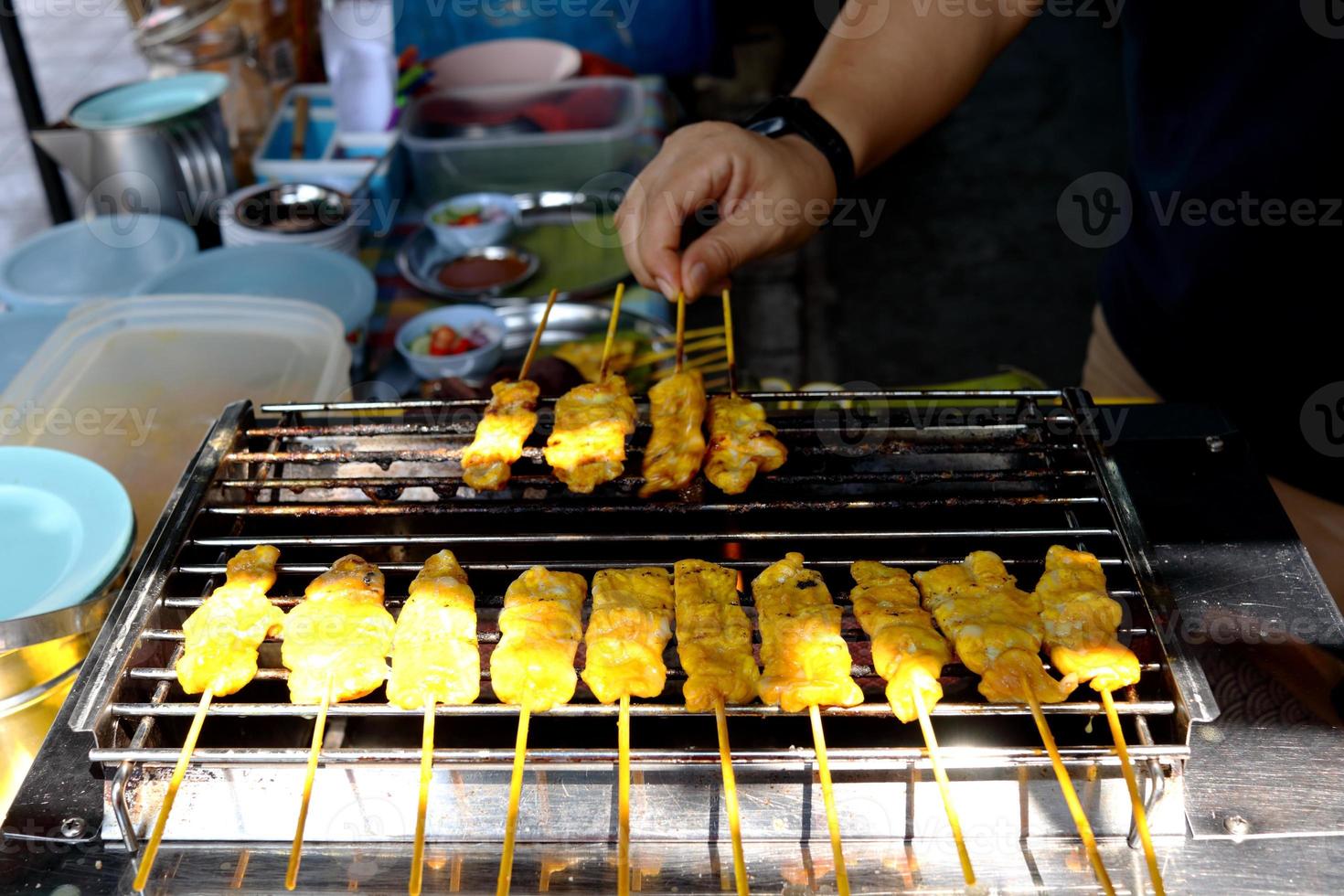I bastoncini di maiale satay stanno grigliando in fila su una torrefazione inossidabile per la vendita, cibo di strada in Thailandia. foto
