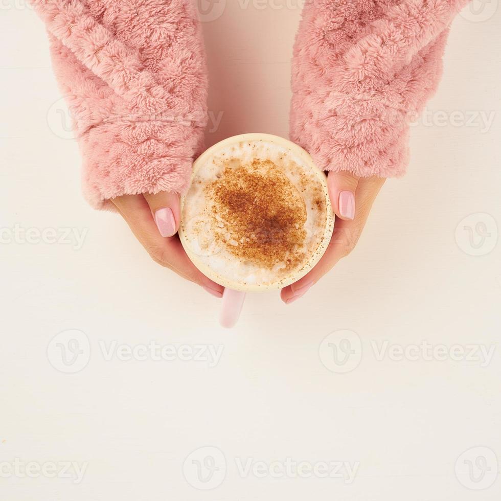 caffè caldo mattutino in una fredda mattina autunnale, mani che tengono la tazza con un drink, atmosfera accogliente, vista dall'alto, spazio per la copia foto