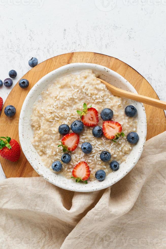 porridge di farina d'avena rustico con frutti di bosco, dieta dash, su fondo di legno bianco vista dall'alto foto