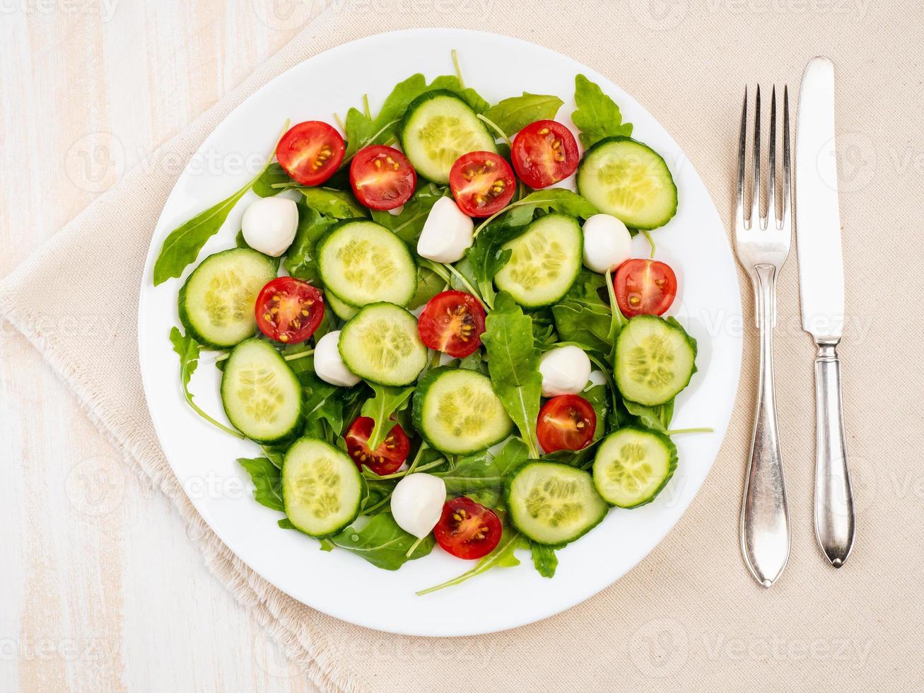 insalata fresca con pomodori, cetrioli, rucola, mozzarella. olio con spezie, vista dall'alto foto