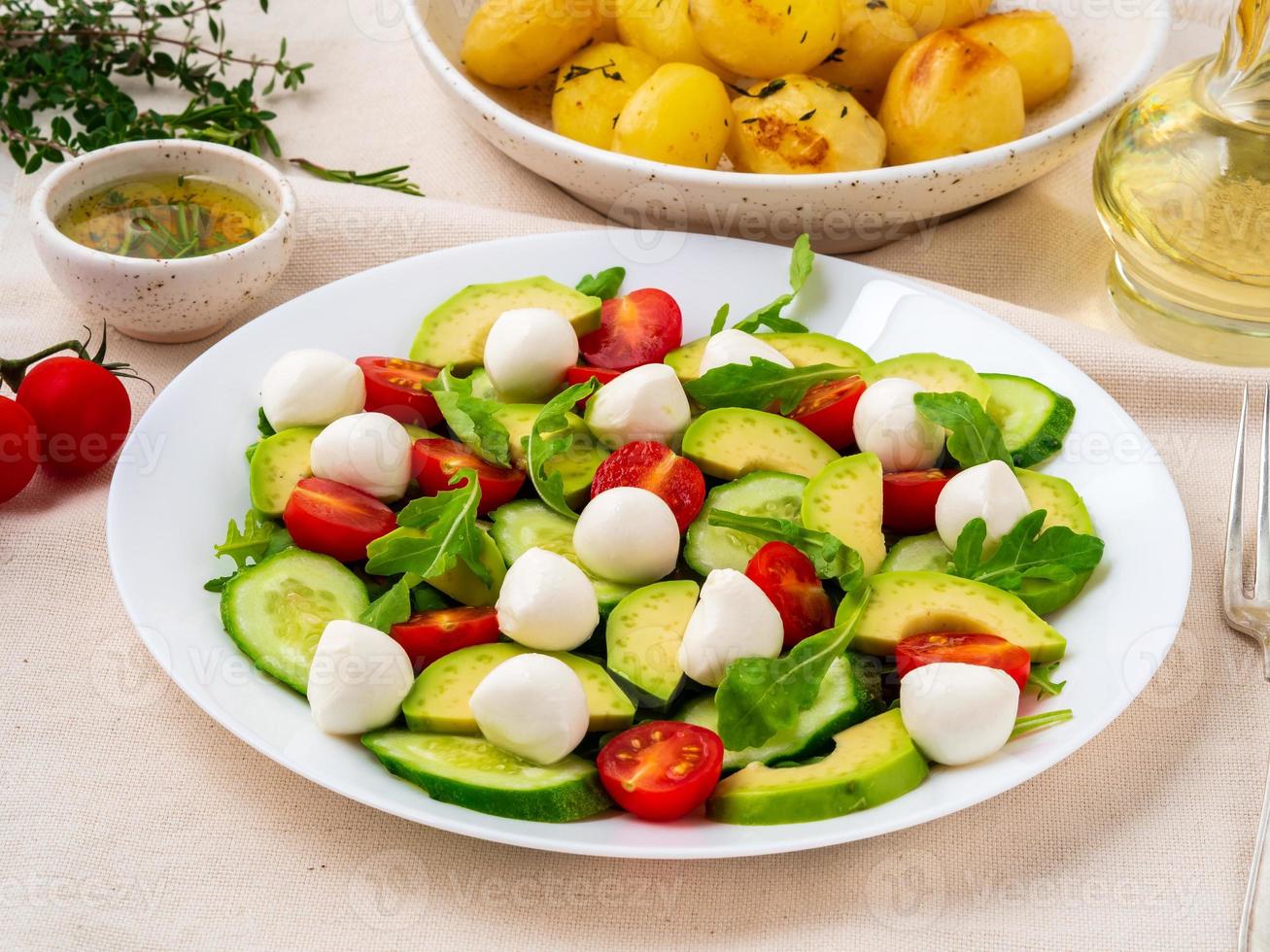 insalata fresca con pomodori cetrioli rucola mozzarella e avocado. olio alle spezie, foto