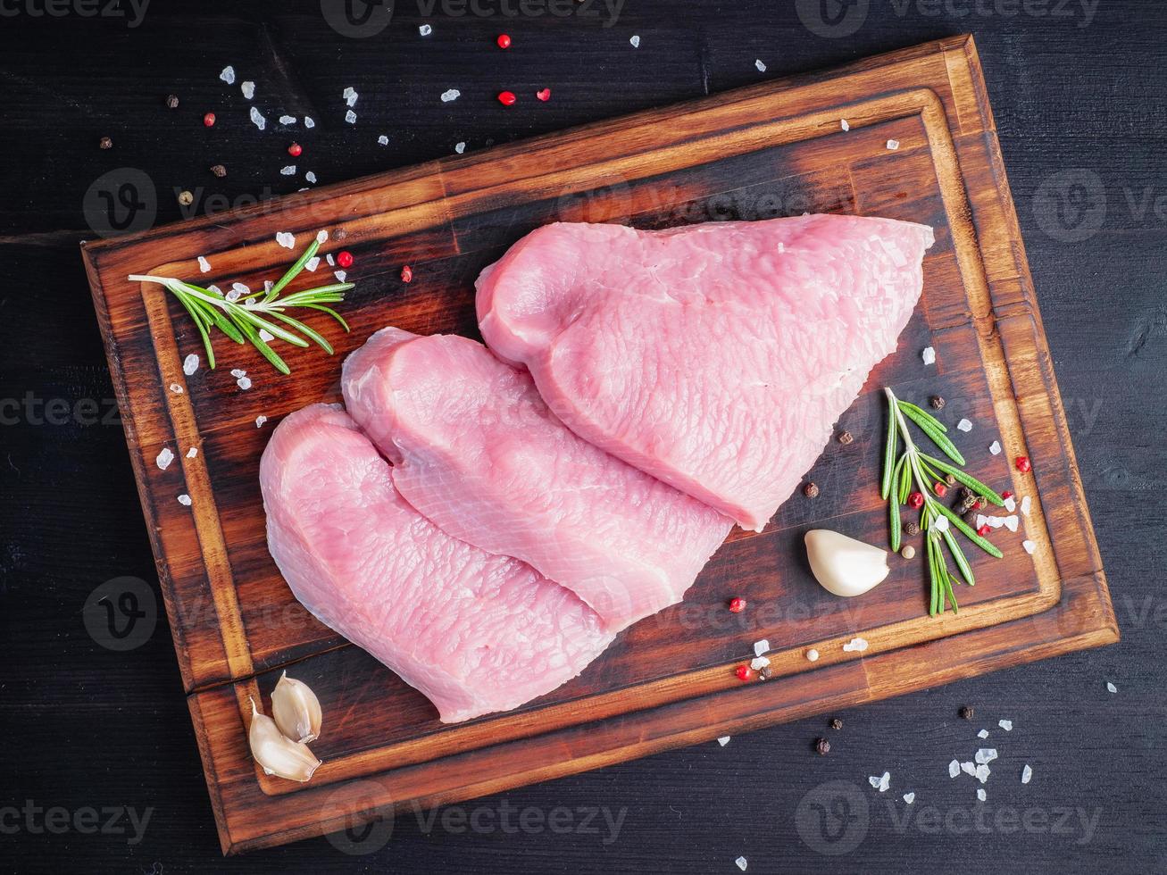 bistecca di tacchino, filetto crudo su tagliere su fondo scuro, carne con foto