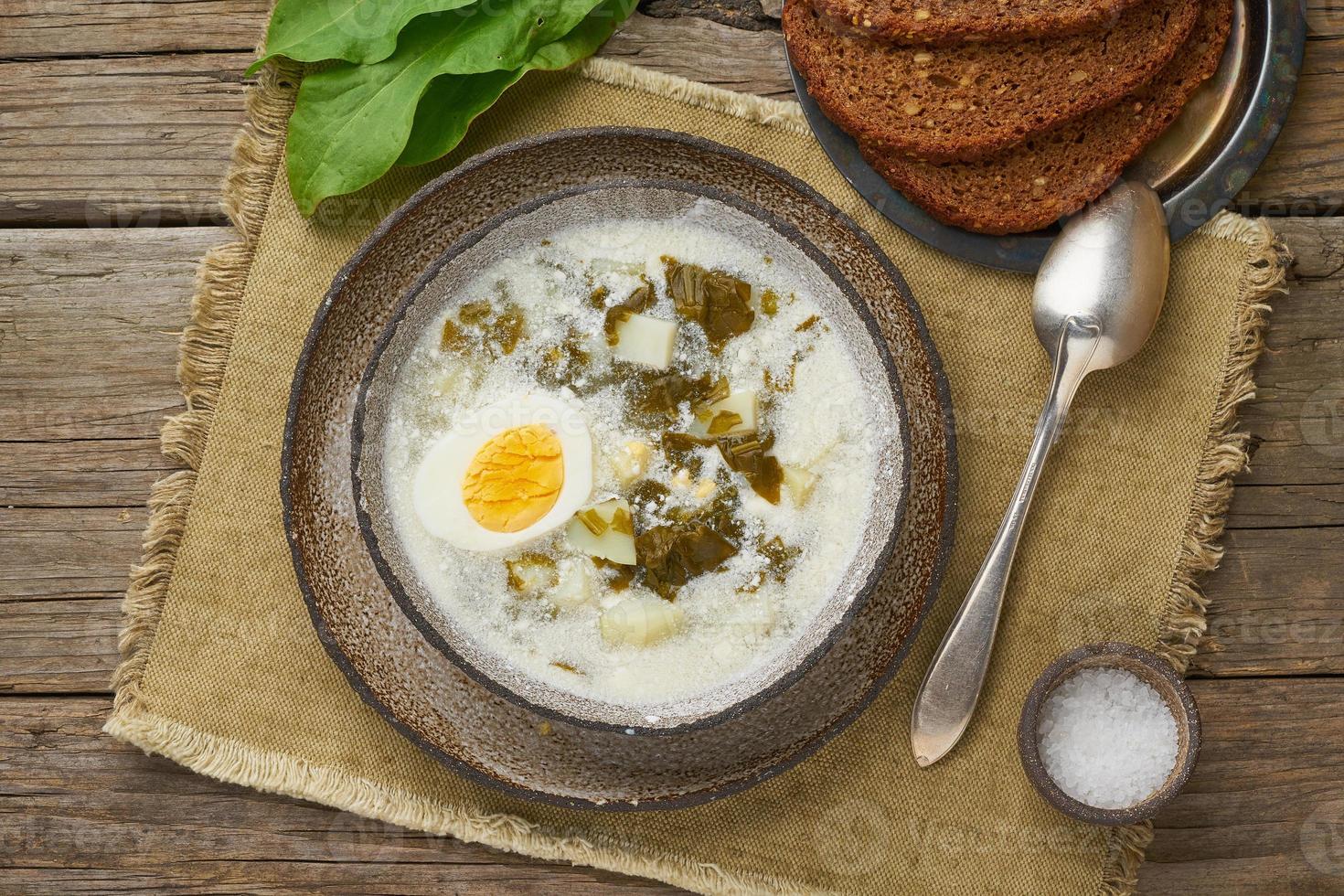 zuppa di acetosa con panna e uova, fondo in legno, vista dall'alto foto