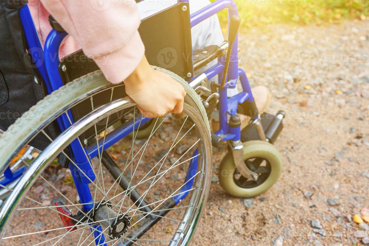 donna con handicap a mano in sedia a rotelle su strada nel parco dell'ospedale in attesa di servizi per i pazienti. ragazza paralizzata irriconoscibile su sedia per invalidi per disabili all'aperto. concetto di riabilitazione. foto