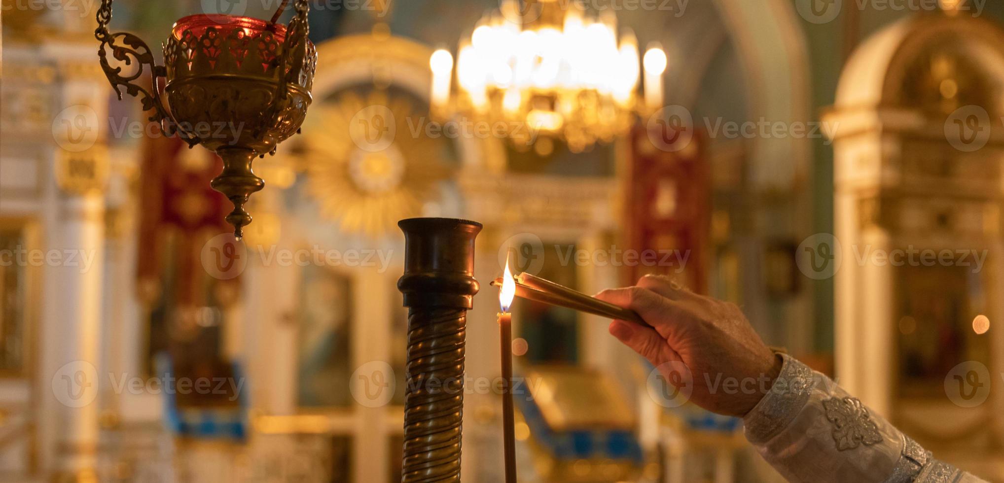 Chiesa ortodossa. cristianesimo. mano del sacerdote che accende candele accese nella tradizionale chiesa ortodossa alla vigilia di Pasqua o a Natale. religione fede pregare simbolo. foto