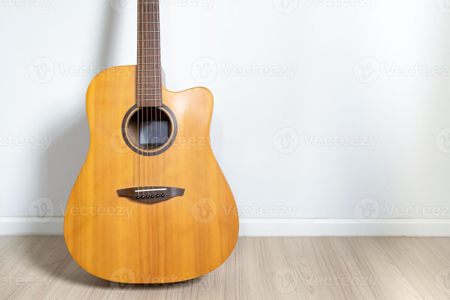 una chitarra acustica dreadnought era appoggiata al muro bianco dello sfondo della stanza. foto