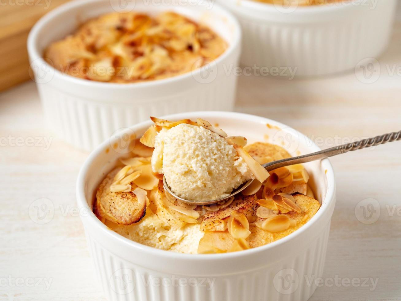 cheesecake sul tavolo di legno bianco in cucina. delicato dessert di cagliata con mele, scaglie di mandorle foto