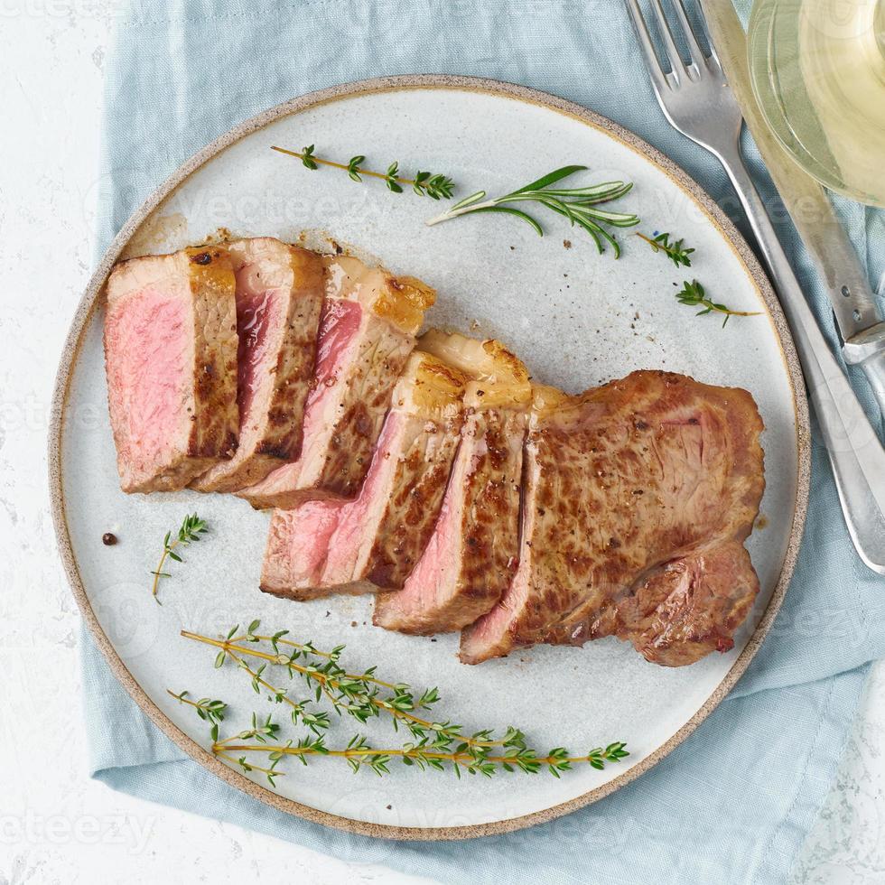 bistecca di manzo dieta cheto-chetogenica, controfiletto su piastra grigia su sfondo bianco. cibo paleo foto