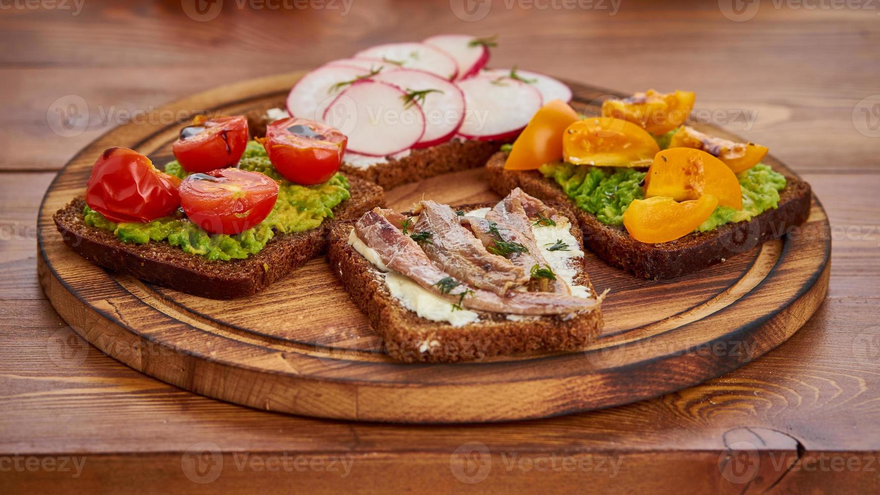 set di smorrebrods con pesce, acciughe, avocado, pomodori, ravanello. foto