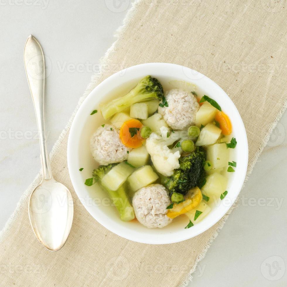 ciotola di zuppa, una tazza di brodo e verdure, polpette di tacchino e pollo, vista dall'alto foto