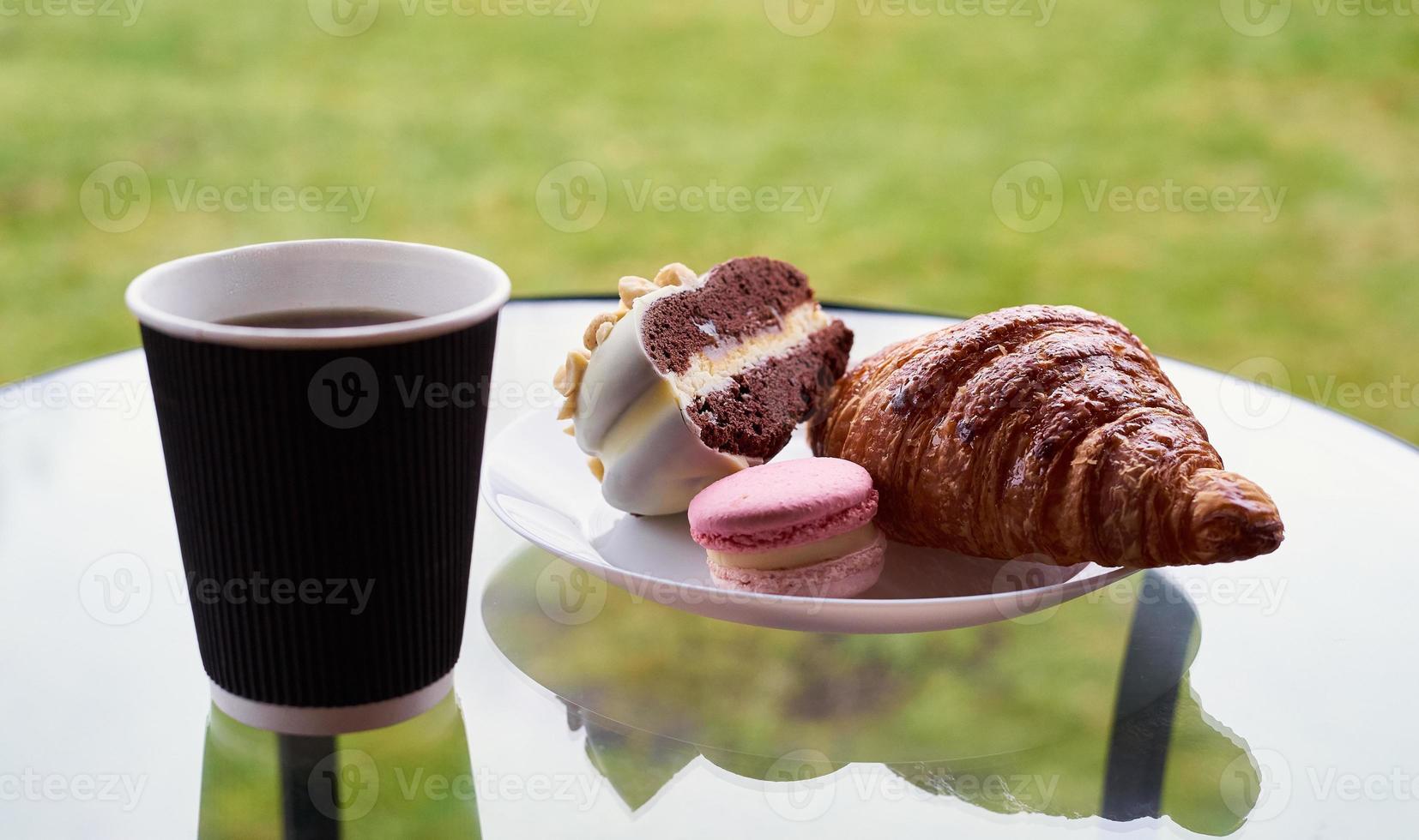 colazione con croissant e dessert, caffè o tè in tazza di plastica, in paese, all'aperto, nella natura. foto