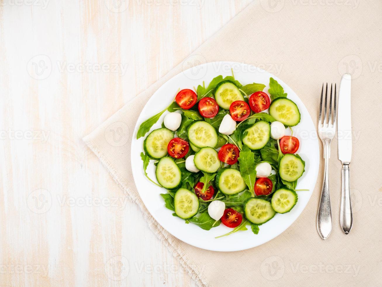 insalata fresca con pomodori, cetrioli, rucola, mozzarella. olio con spezie, vista dall'alto foto