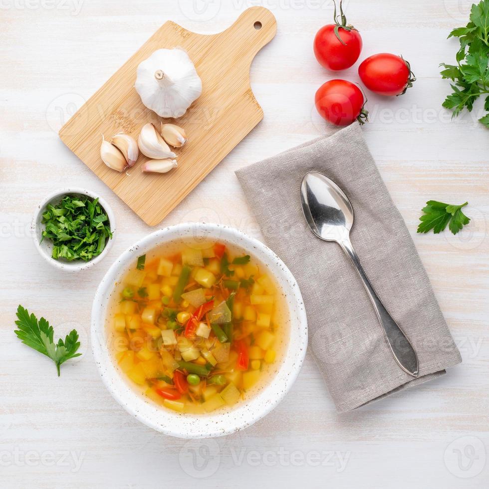 zuppa vegetariana dietetica di verdure primaverili sana, fondo di legno bianco, vista dall'alto, primo piano foto