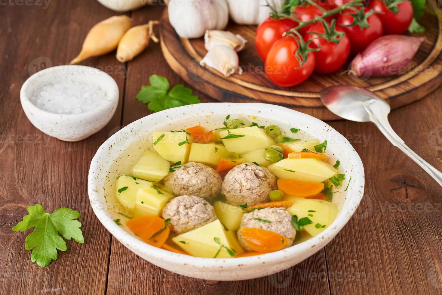 Zuppa di polpette in piatto bianco sul vecchio tavolo marrone rustico in legno, vista laterale foto