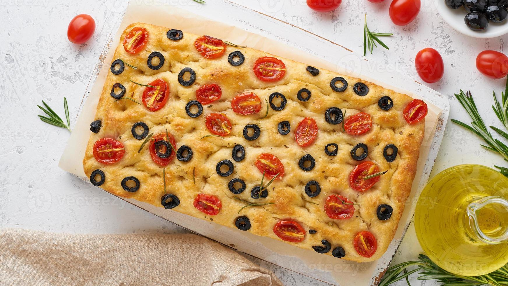 focaccia con pomodori, olive e rosmarino, vista dall'alto. focaccia italiana, bottiglia con olio foto