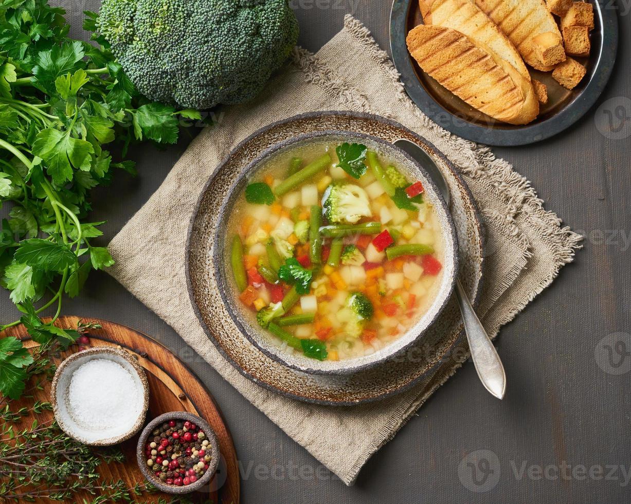 zuppa di verdure, piatto primaverile vegetariano dietetico, tovagliolo di lino, vista dall'alto, sfondo scuro. foto