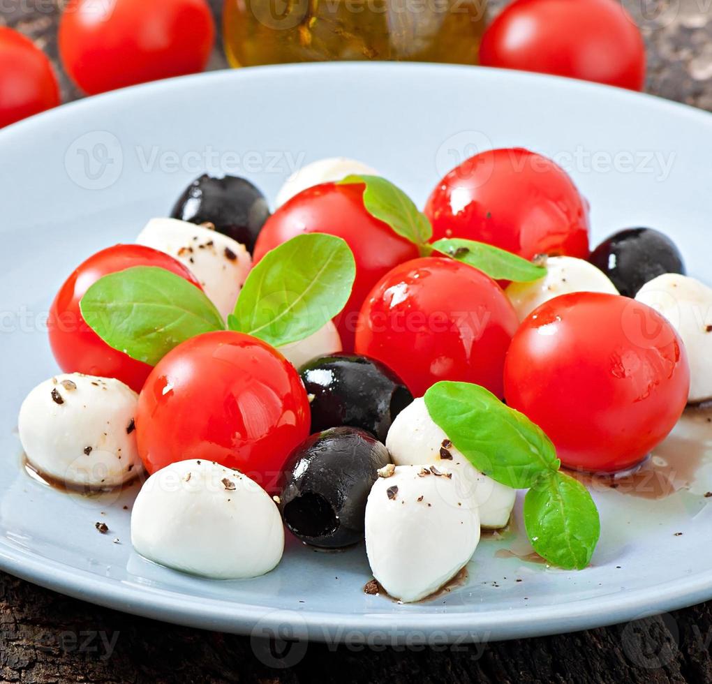 insalata fresca con pomodorini, basilico, mozzarella e olive nere. foto