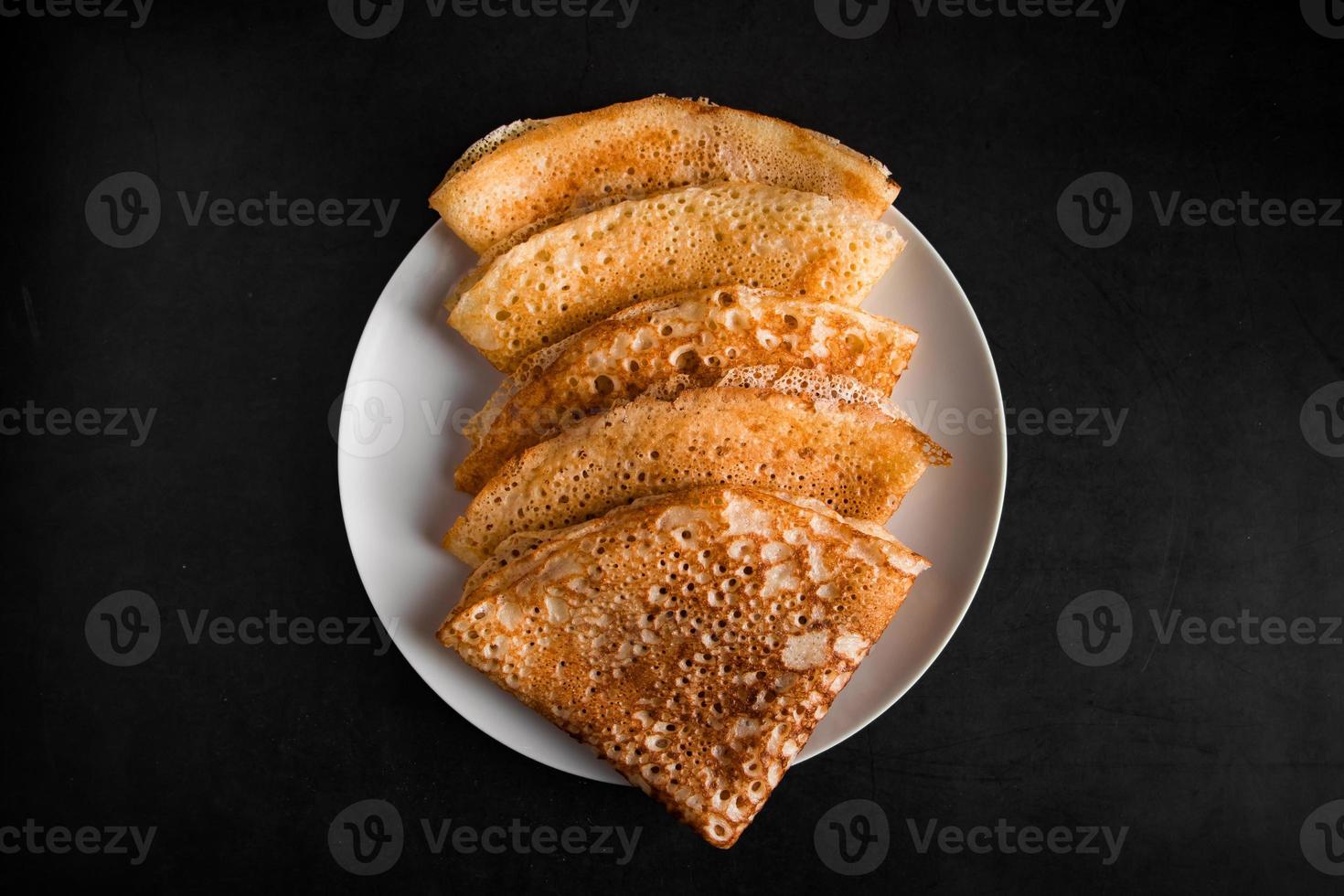 frittelle sottili su un piatto su uno sfondo nero, cibo tradizionale russo. foto