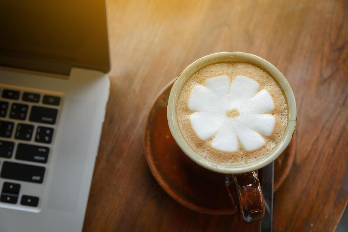 vista dall'alto della tazza di caffè e del laptop sul tavolo di legno nella caffetteria. concetto di affari foto