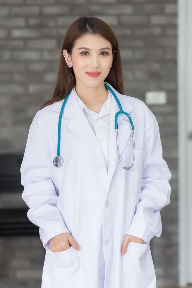 una giovane donna medico indossa un camice da laboratorio e uno stetoscopio in ospedale. foto