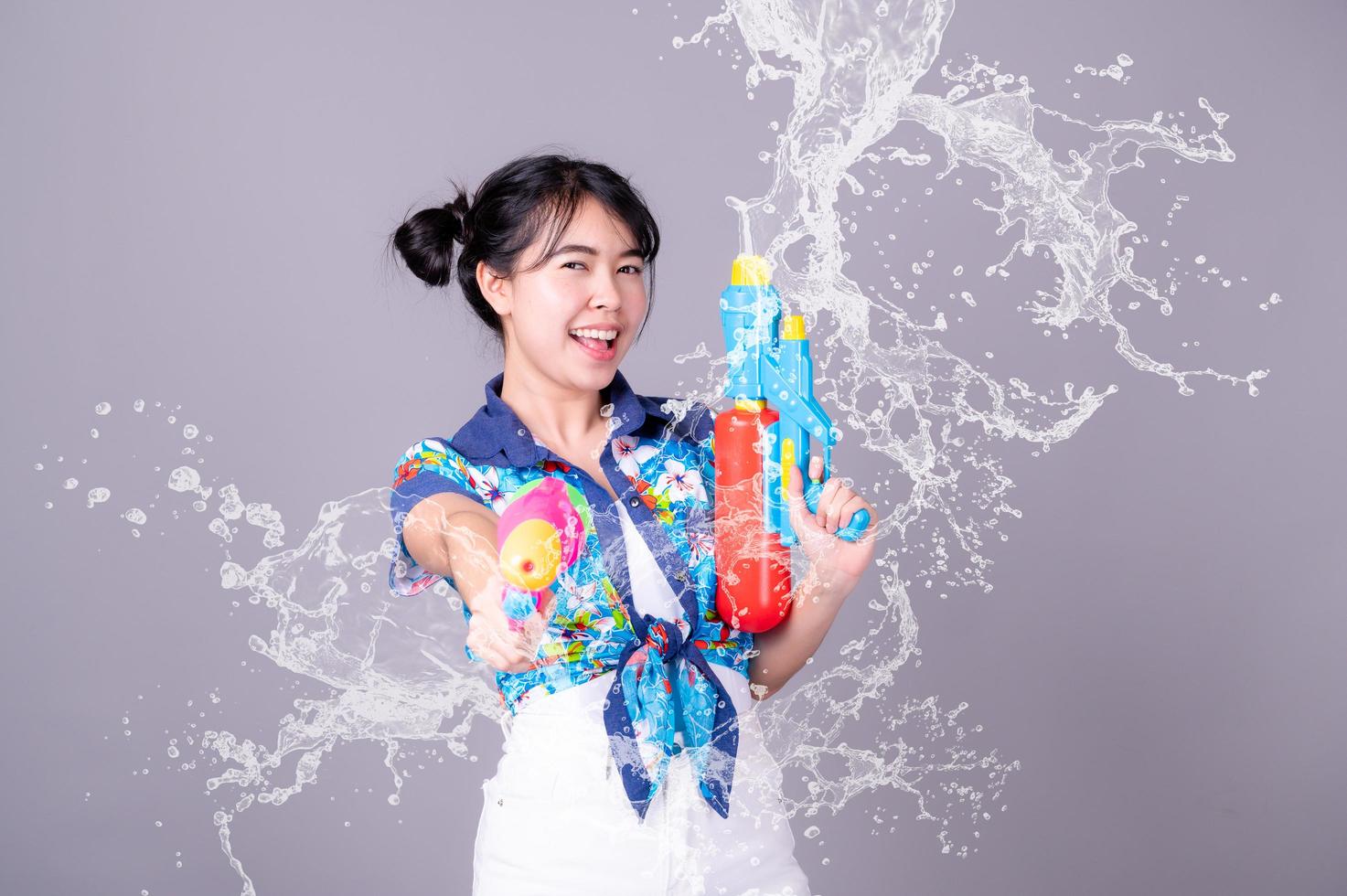 una bella donna asiatica mostra un gesto mentre tiene in mano una pistola ad acqua di plastica durante il festival di Songkran foto