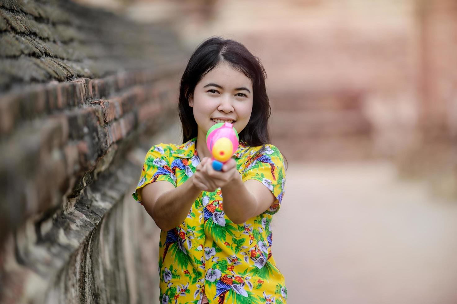 belle donne asiatiche tengono pistole ad acqua di plastica in un antico tempio durante il Songkran, il festival dell'acqua più bello e divertente della Thailandia foto