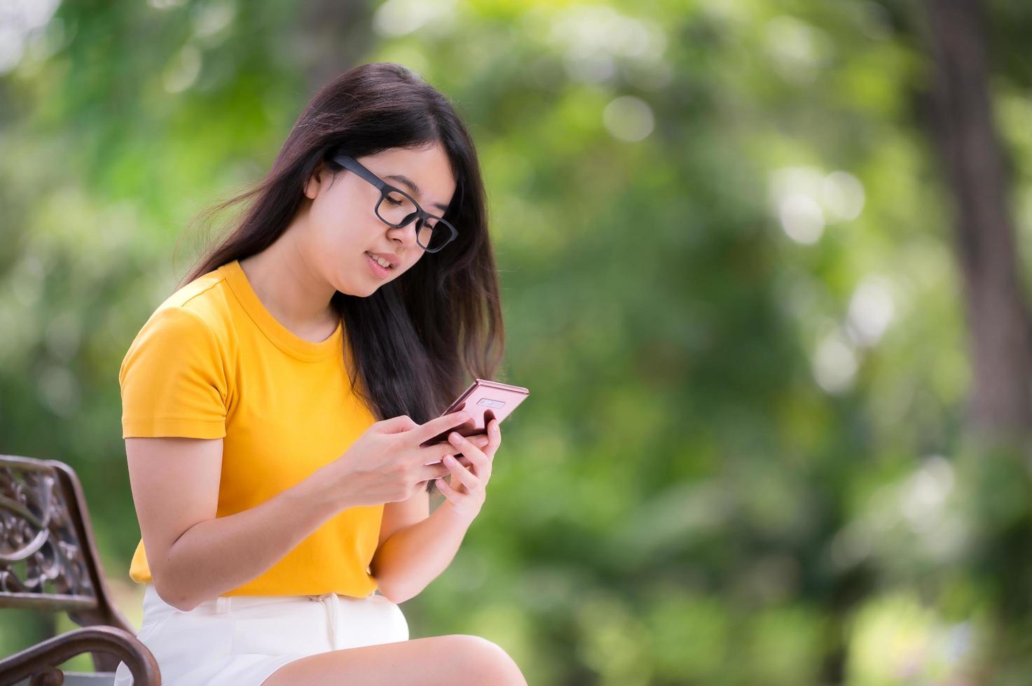 bella donna asiatica sdraiata in giardino e utilizzando un telefono cellulare, può cercare informazioni o fare acquisti online su Internet foto