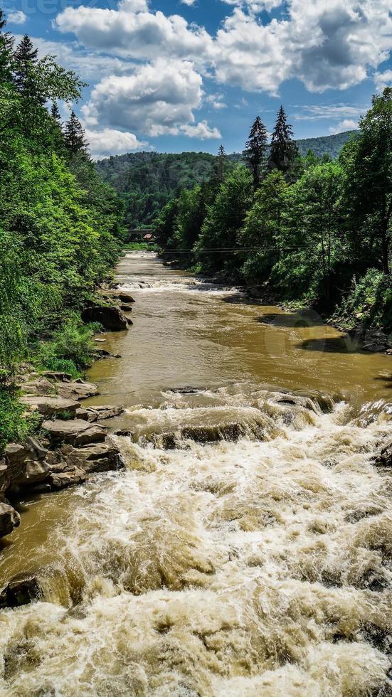 forte flusso e ebollizione dell'acqua nel fiume di montagna con schizzi. flusso veloce nei carpazi, ucraina. pietre in un fiume di montagna. sfondo naturale dell'acqua. avvicinamento. foto