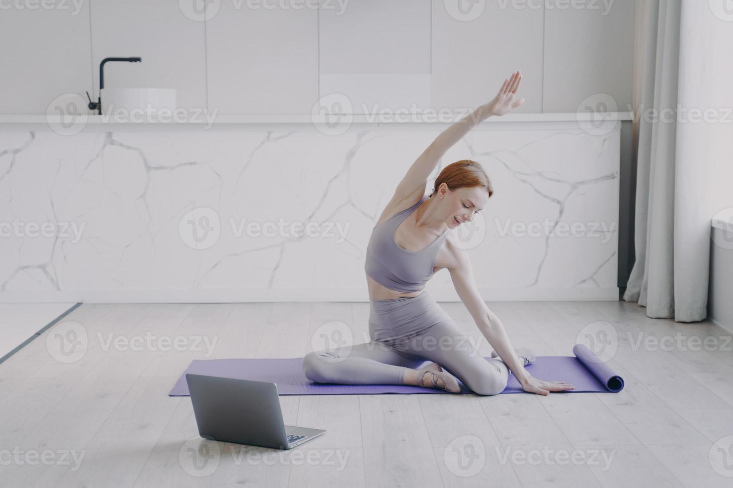la giovane donna sta allungando e praticando yoga sul pavimento. sport e stile di vita sano in quarantena. foto