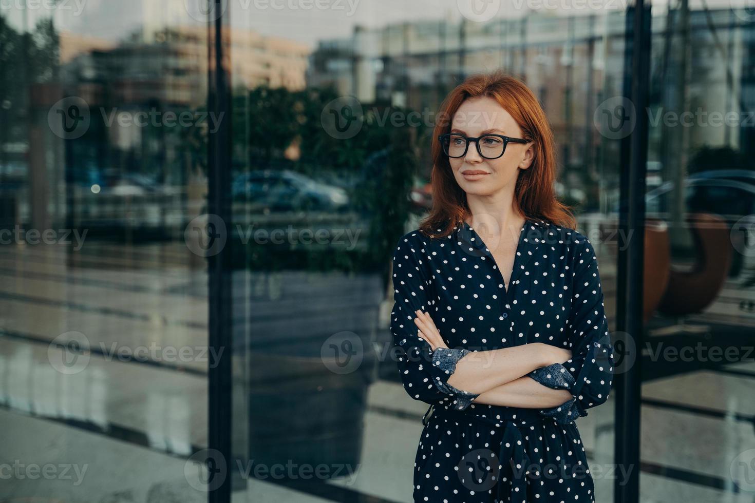 bella giovane donna rossa si trova vicino alla finestra dell'edificio per uffici foto