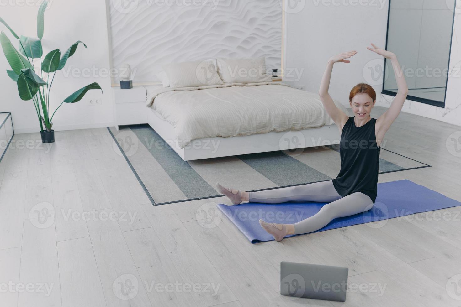donna che esercita il balletto del corpo tenendo le mani in alto. formazione personale a distanza davanti alla telecamera. foto