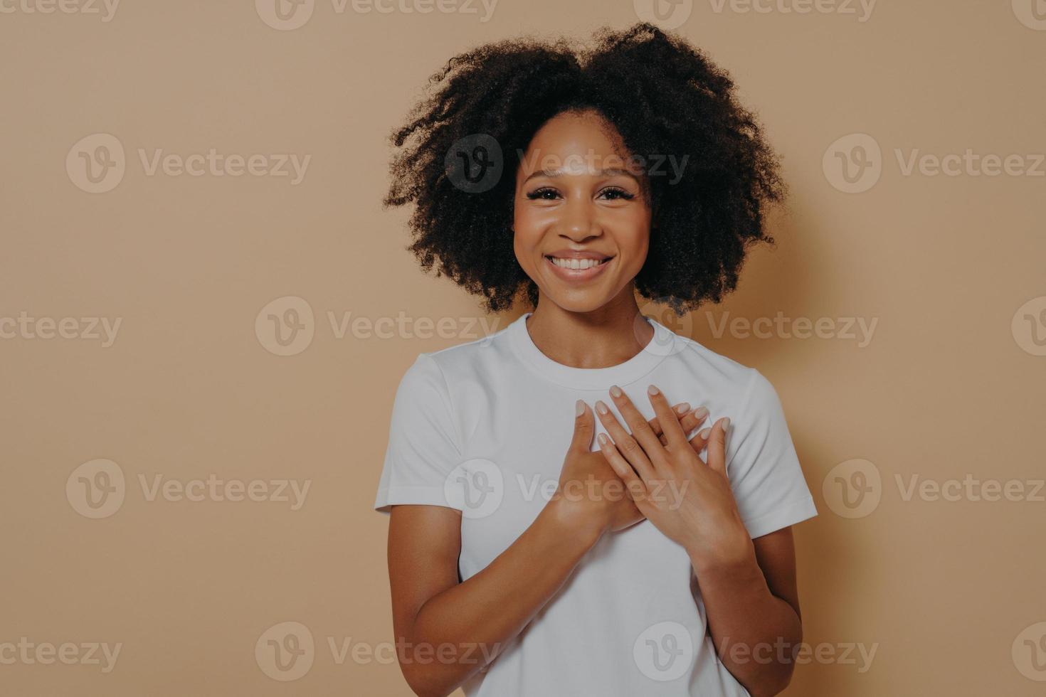 grata giovane donna africana isolata su sfondo giallo studio che mostra apprezzamento e amore foto