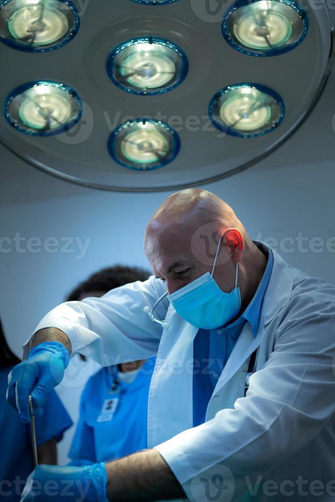 un professore di medicina insegna chirurgia a studenti di medicina che lavorano foto