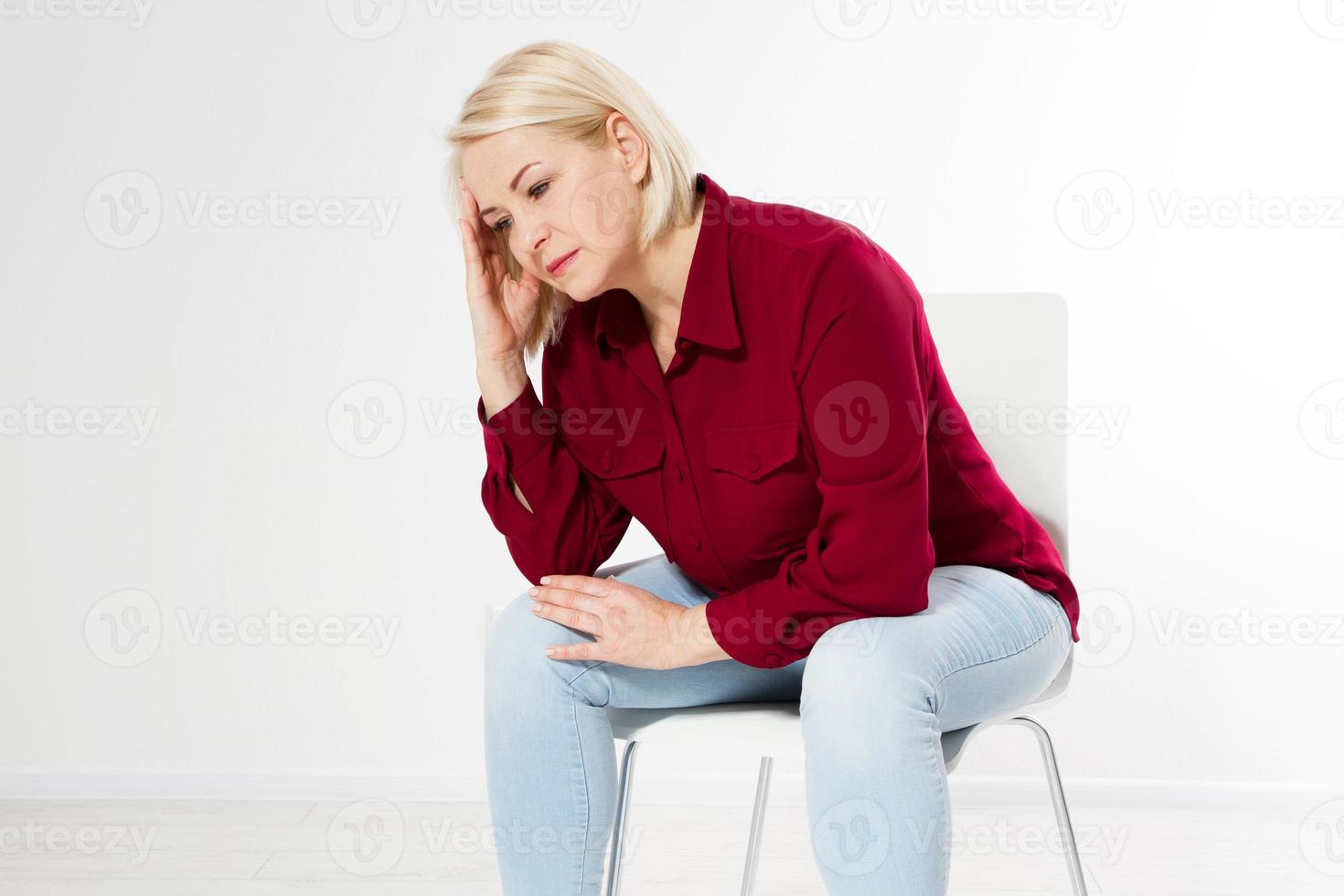donna di mezza età mal di testa emicrania, bella donna di mezza età triste si siede su una sedia, ha mal di testa foto