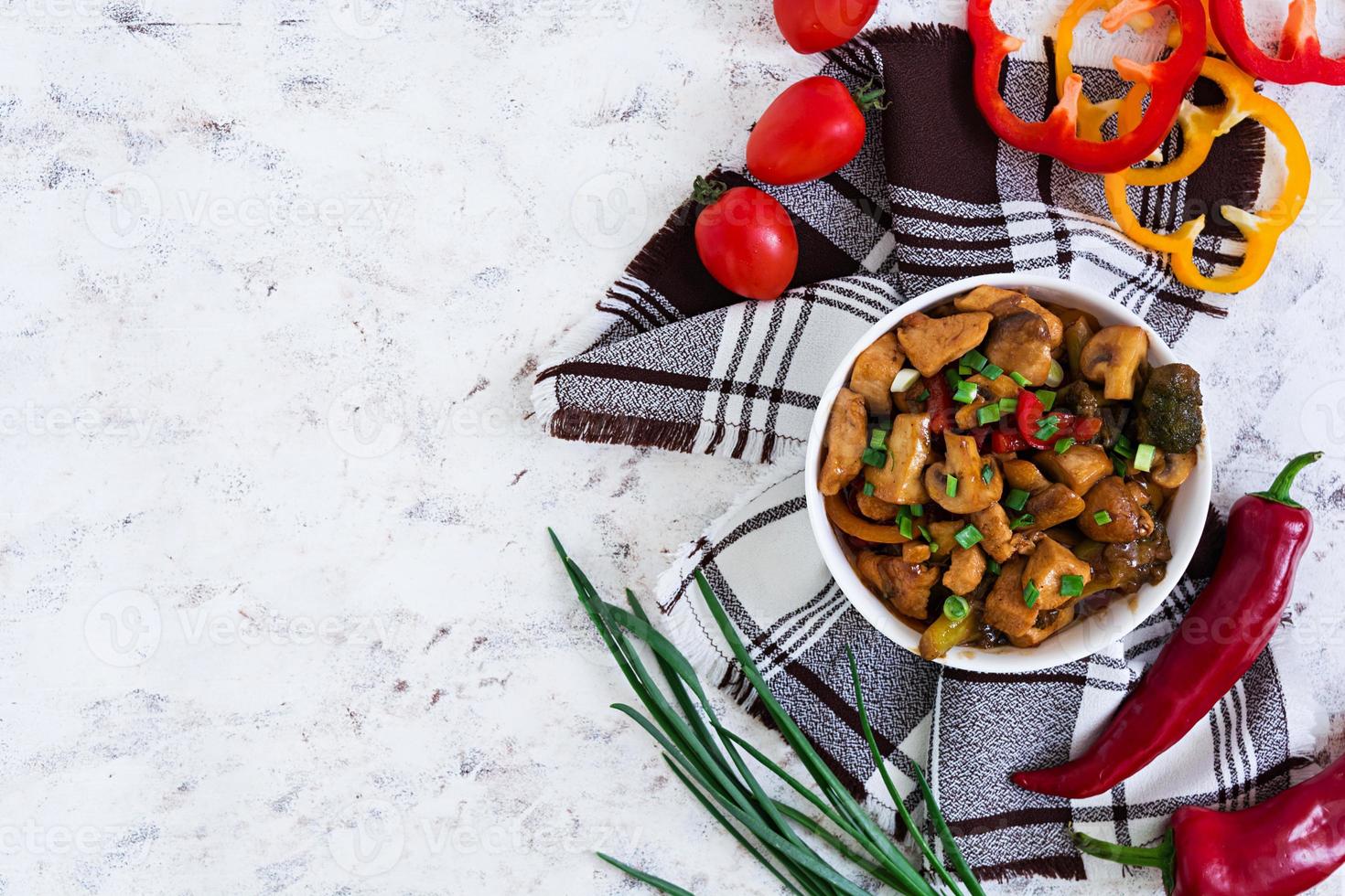 soffriggere il pollo con peperoni e funghi su sfondo bianco. vista dall'alto foto