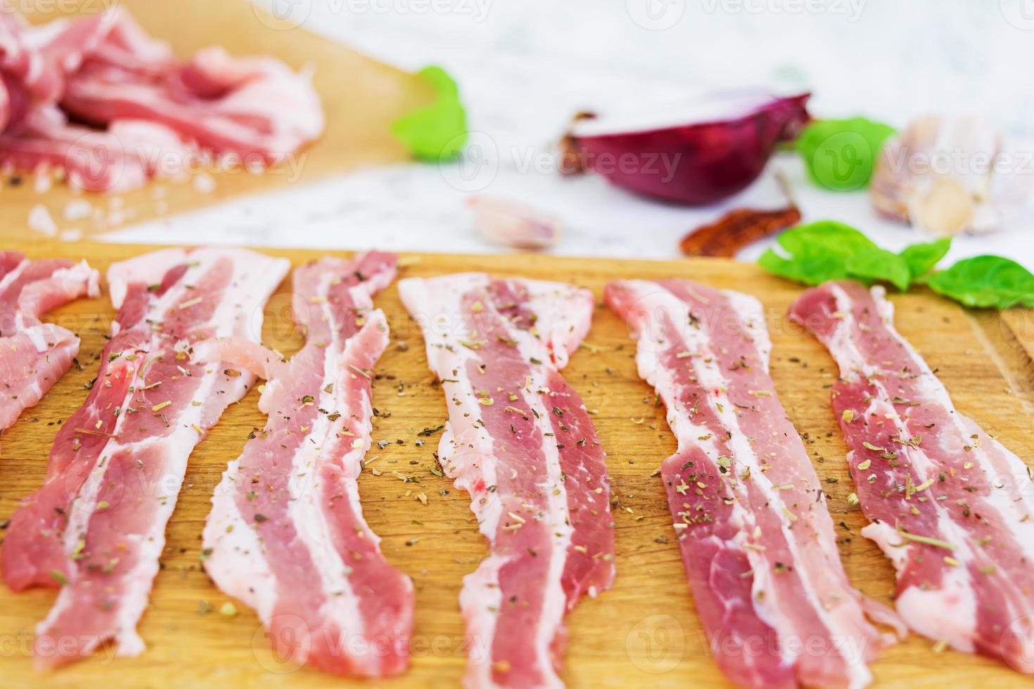 pancetta fresca affettata con spezie su sfondo bianco foto